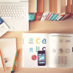 Image of a Macbook an iphone and books on a desk